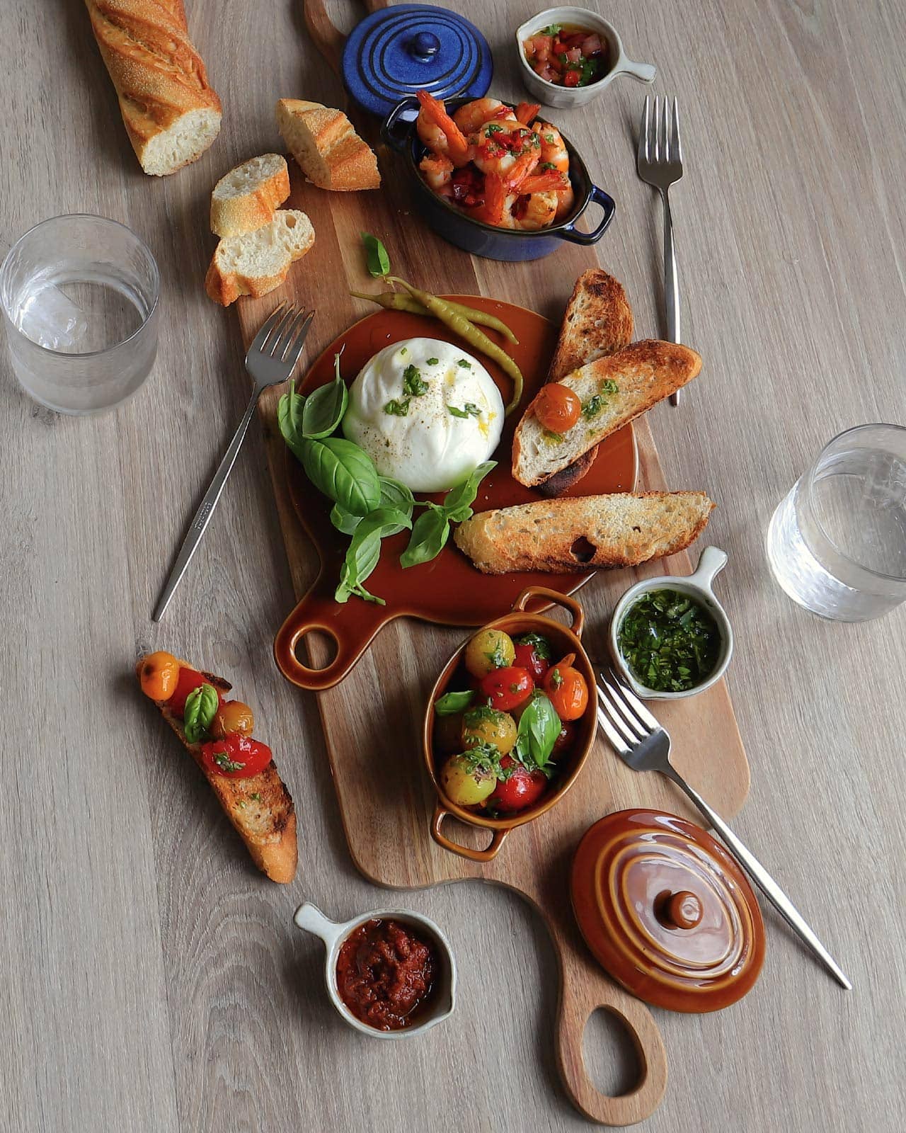 Toasts van burrata-kaas met tomaat en scampipannetje met chili en koriander